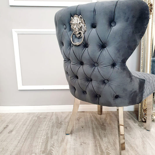Grey velvet dining chair back with deep button tufting and a lion-head ring knocker