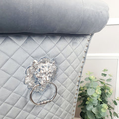 Close-up of a velvet dining chair's quilted back and silver lion-head ring pull