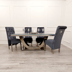 Arial dining table with pale stone top and curved metallic pedestal, shown with dark chairs