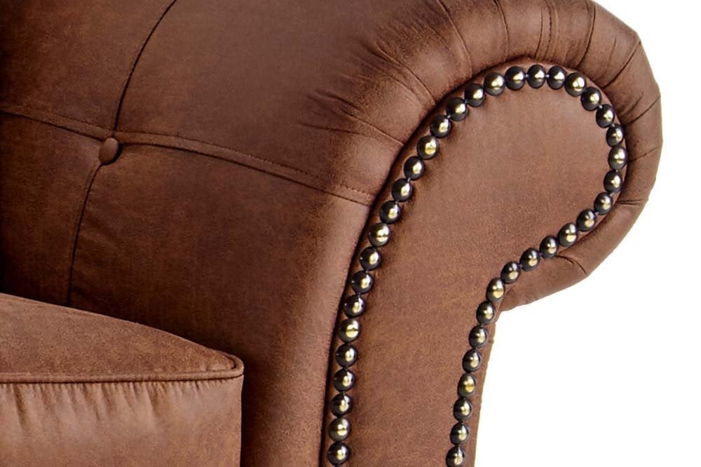 Close-up of brown sofa's rolled arm with decorative nailhead trim