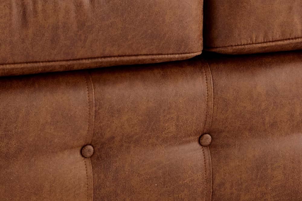 Close-up of the sofa's brown upholstery with stitched seams and button tufting