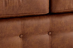 Close-up of brown sofa upholstery with tufted buttons and stitched panels