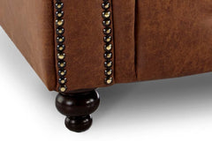 Close-up of armchair's turned wooden foot and nailhead-trimmed upholstery