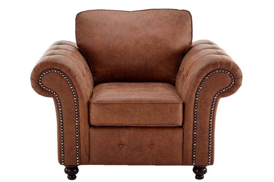 Front view of brown upholstered armchair with rolled arms and nailhead trim