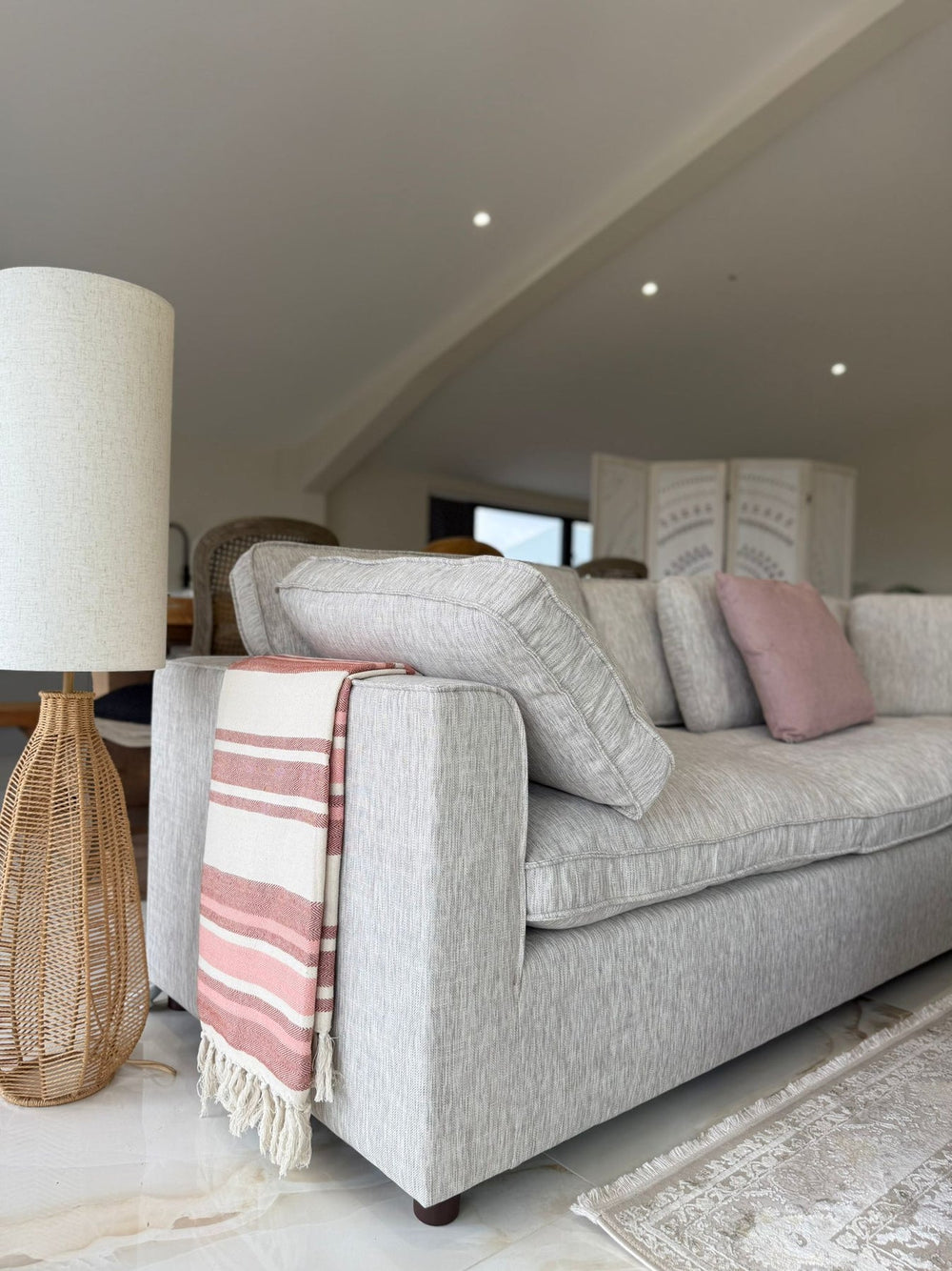 Light gray corner sofa with broad arm and loose back cushions