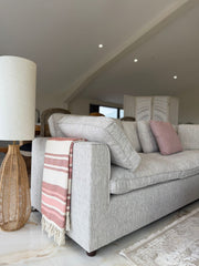 Light gray corner sofa with broad arm and loose back cushions