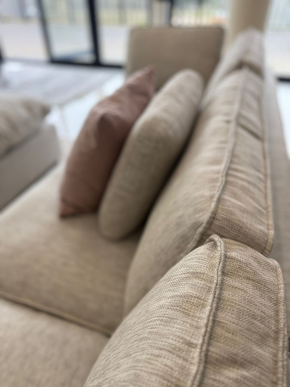 Close-up of corner sofa's textured fabric and loose back cushions
