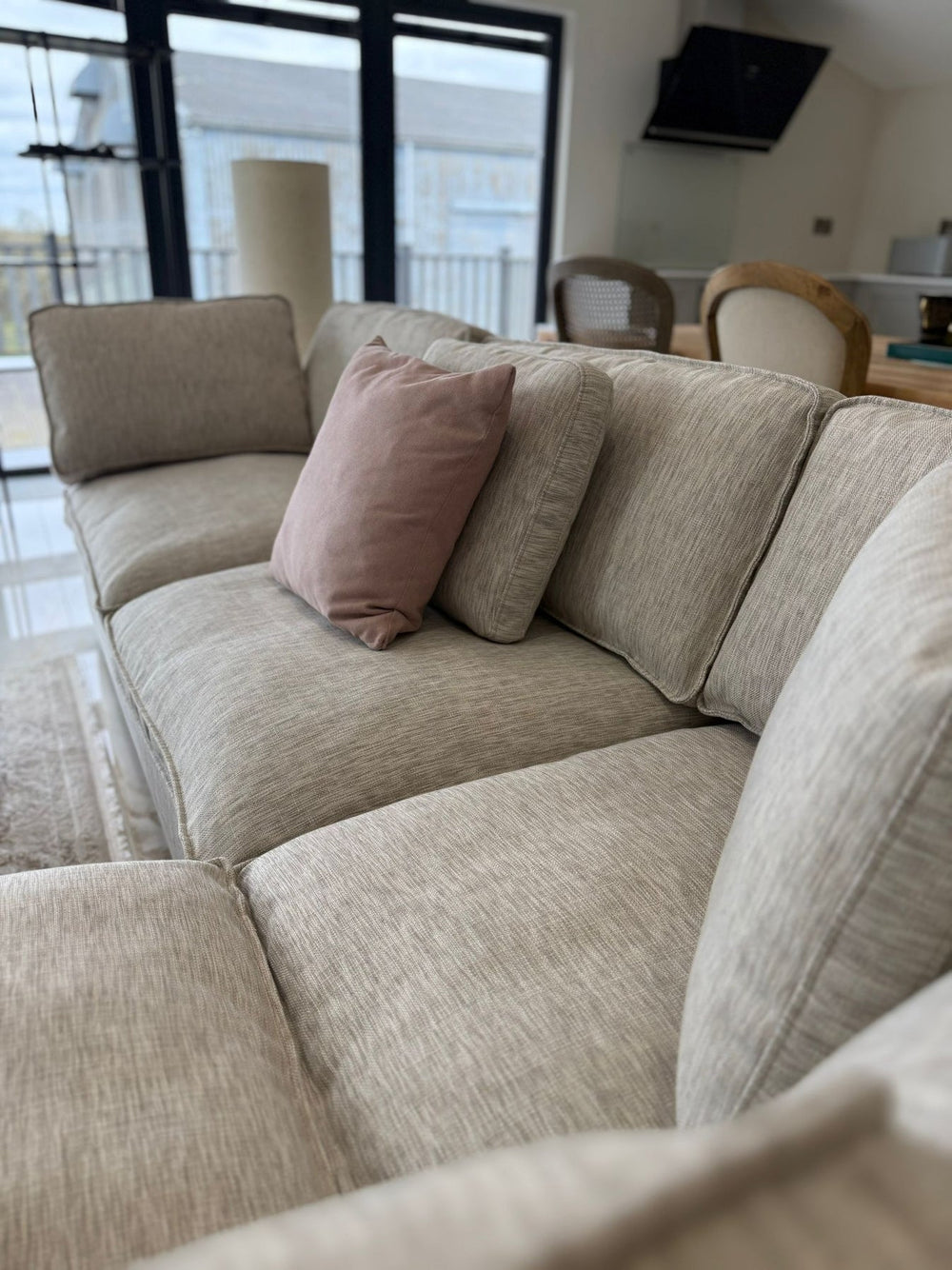 Corner sofa seating with textured light gray upholstery and loose cushions