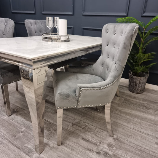 Light gray velvet dining chair with button-tufted back, nailhead trim and light wood legs