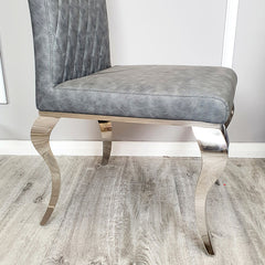 Gray leather dining chair with a padded seat and curved polished metal legs