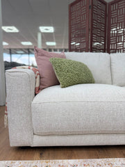 Marlow corner sofa seat and broad arm in light gray woven upholstery, with cushions.