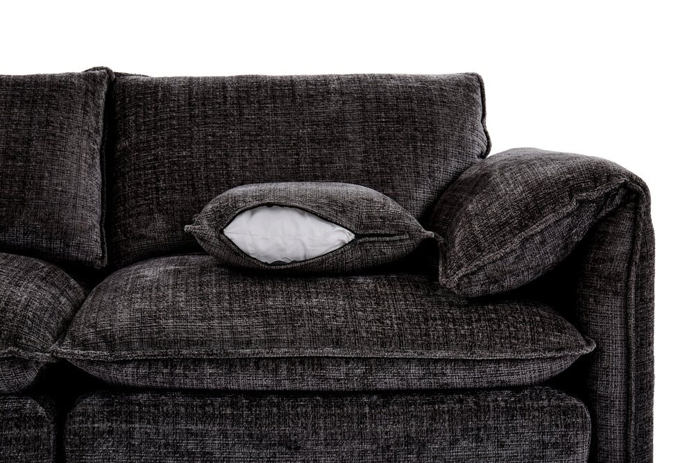 Dark gray corner sofa close-up showing a textured fabric seat, back cushions, and loose pillow.