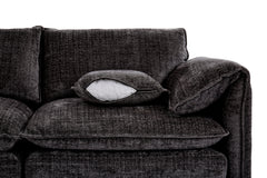 Dark gray corner sofa close-up showing a textured fabric seat, back cushions, and loose pillow.
