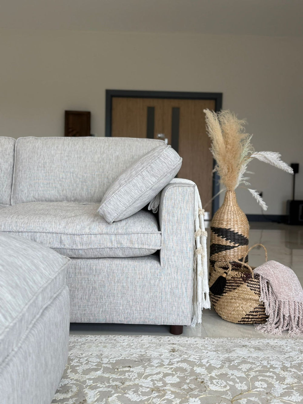 Light gray sofa end with a wide arm and loose cushion