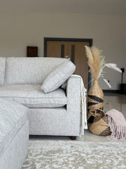 Light gray sofa end with a wide arm and loose cushion