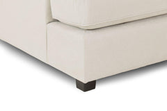 Close-up of beige sofa upholstery, seat cushion seam, and dark foot